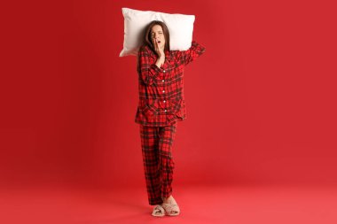 Kırmızı arka planda yastıklı şık pijamalı bir kadın.