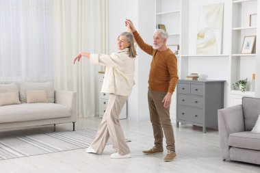Mutlu yaşlı çift evde dans ediyor.