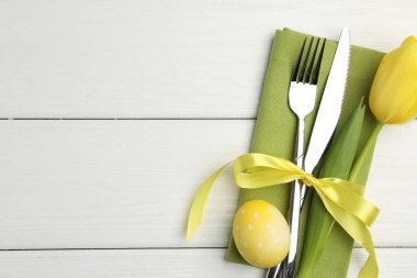 Paskalya sofrası. Lale ve beyaz ahşap arka planda boyalı yumurta ile güzel gümüş takımlar, üst manzara. Metin için boşluk