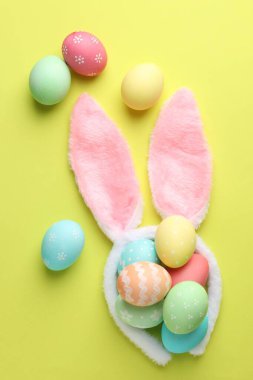 Mutlu Paskalyalar. Sevimli tavşan kulakları ve sarı arka planda boyanmış yumurtalar.