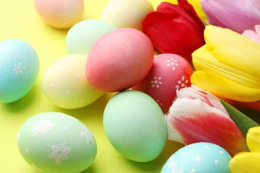 Boyalı Paskalya yumurtaları ve açık yeşil arka planda güzel laleler. Yakın plan.