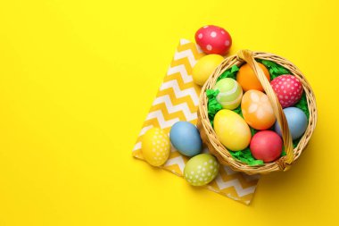 Sarı arka planda boyanmış yumurtaları olan Paskalya sepeti, düz. Metin için boşluk