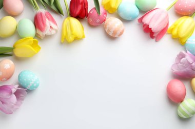 Boyalı Paskalya yumurtaları ve beyaz arka planda güzel laleler. Metin için boşluk