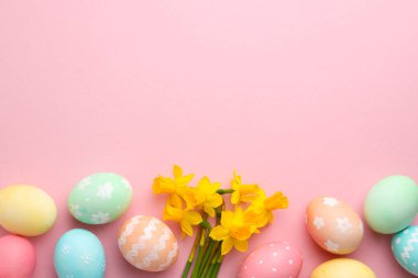 Paskalya yumurtaları ve pembe arka planda güzel nergisler, düz yatak. Metin için boşluk