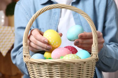 Paskalya sepetinde yumurta boyalı bir kadın, kapalı bir masada, yakın plan.