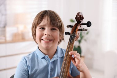 Evde viyolonsel çalan sevimli küçük çocuk.