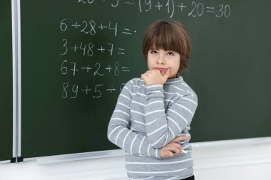 Matematik ödevi için tahtaya yakın düşünceli bir öğrenci.