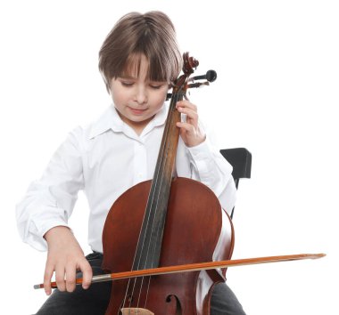 Küçük çocuk beyaz arka planda sandalyede keman çalıyor.