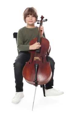 Küçük çocuk beyaz arka planda sandalyede keman çalıyor.