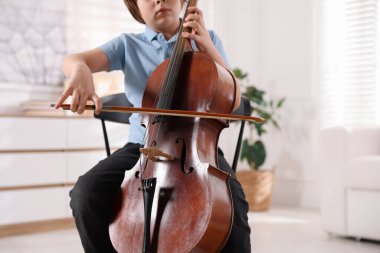 Evdeki sandalyede keman çalan küçük çocuk, yakın plan. Metin için boşluk