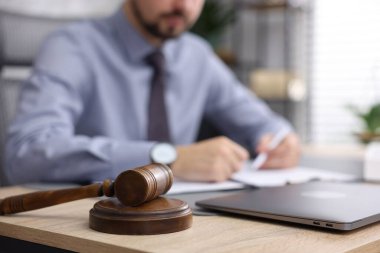 Ofisteki ahşap masada çalışan noter, dizüstü bilgisayara ve tokmağa odaklan