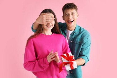 Sevgililer Günü. Mutlu genç adam pembe arka planda kız arkadaşına sürpriz yapıyor.