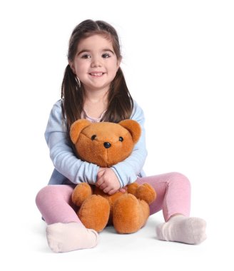 Beyaz arka planda oyuncak ayısı olan sevimli küçük bir kız.