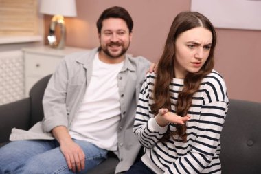 Utangaç kadın evdeki kanepede flört eden adamı görmezden geliyor, seçici odaklı.