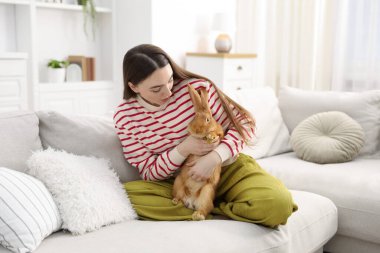 Evdeki kanepede sevimli tavşanlı mutlu kadın.