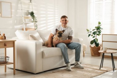 Evdeki kanepede dinlenen sevimli köpeğiyle genç bir adam.