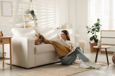 Evdeki kanepenin yanında tatlı köpeği olan bir kadın.