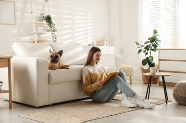 Evdeki kanepenin yanında tatlı köpeği olan bir kadın.