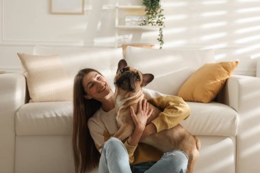 Evdeki kanepenin yanında sevimli köpeği olan bir kadın.