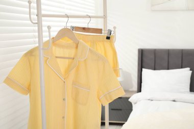 İçerideki yatağın yanındaki askıda asılı şık sarı pijamalar, yakın plan. Metin için boşluk