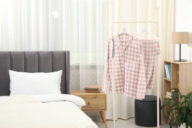 Havalı pijamalar ve uyku maskesi yatağın yanındaki rafta asılı.