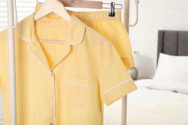 İçerideki yatağın yanındaki askıda asılı şık sarı pijamalar, yakın plan. Metin için boşluk