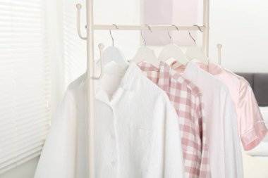 Yatağın yanındaki askıda asılı şık pijama gömlekler, yakın plan.