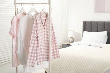 İçerideki yatağın yanındaki askıda asılı duran şık pijama gömlekler, metin için yer