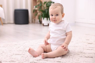 Evde yerde oturan şirin bir bebek.