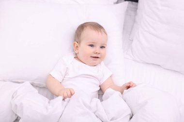 Evdeki yatakta uzanmış şirin küçük bebek, üst manzara.