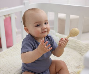 Evinde ahşap çıngıraklı şirin bir bebek.