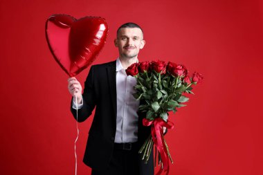 Sevgililer Günü kutlaması. Kırmızı arka planda gül buketi ve kalp şeklinde balonu olan bir adam.
