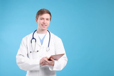 Açık mavi arkaplanda tableti olan tıbbi asistanın portresi, metin için boşluk