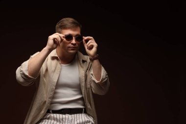 Moda modeli. Siyah arkaplana karşı duran güneş gözlüklü yakışıklı adam, metin için boşluk