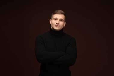 Moda modeli. Koyu kahverengi arka planda poz veren yakışıklı bir adamın portresi.