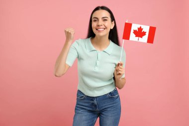 Pembe arka planda Kanada bayrağı taşıyan mutlu kadın.