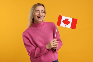 Turuncu arka planda Kanada bayrağı olan mutlu kadın.