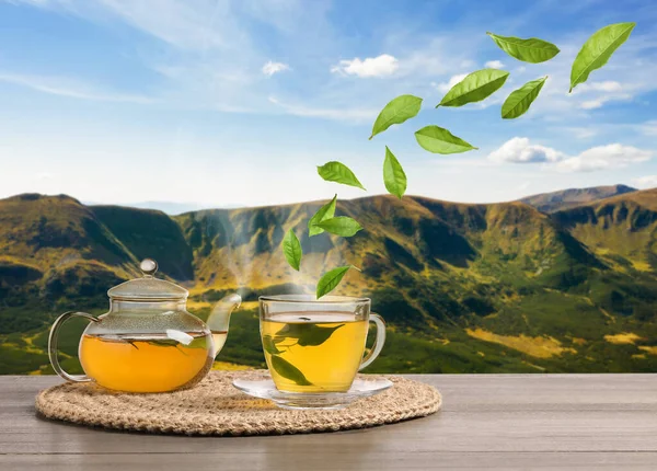 Dağlardaki masada taze demlenmiş çay. Havada uçuşan yeşil yapraklar