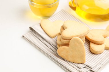 Lezzetli kalp şeklinde tereyağlı kurabiyeler ve beyaz masada çay, yakın plan. Metin için boşluk