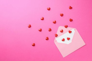 Tebrik kartı ve pembe arka planda dekoratif kalplerle dolu bir zarf. Metin için boşluk