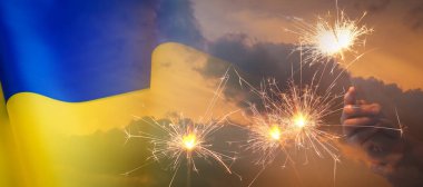 Ukrayna bayrağı ve yanan maytaplar, gün batımı gökyüzü ile çifte çekim. Ulusal bayram kutlaması