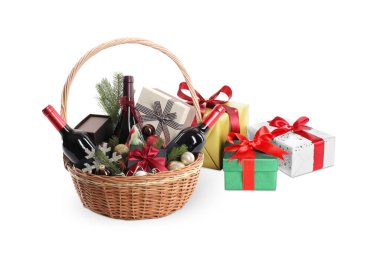 İçinde şarap şişeleri, Noel süsü ve beyaza izole edilmiş hediyeler olan hediye sepeti.