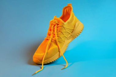 Açık mavi arka planda renkli şık bir spor ayakkabı, yakın plan.