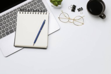 Ofis işyeri. Kırtasiye malzemeleri, dizüstü bilgisayar, bardaklar, kahve ve beyaz arka planda çiçek dekoru, düz yatak. Metin için boşluk