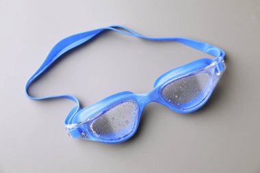 Gri arkaplanda su damlaları olan yüzme gözlükleri, üst görünüm