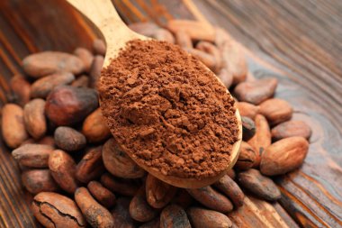 Doğal kakao çekirdeği ve toz tahta masanın üzerinde, yakın plan.