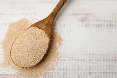 Beyaz ahşap masada kaşıkla kuru maya, üst manzara. Metin için boşluk