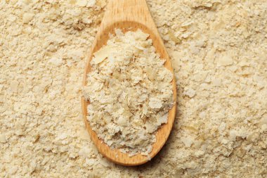 Arka plan olarak kuru maya taneleri ve kaşık, üst görünüm