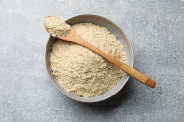 Kavanozda kuru maya taneleri ve gri masada kaşık, üst manzara.