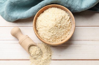 Kuru maya taneleri kasede ve kepçeyle tahta masada, düz bir şekilde yatar.